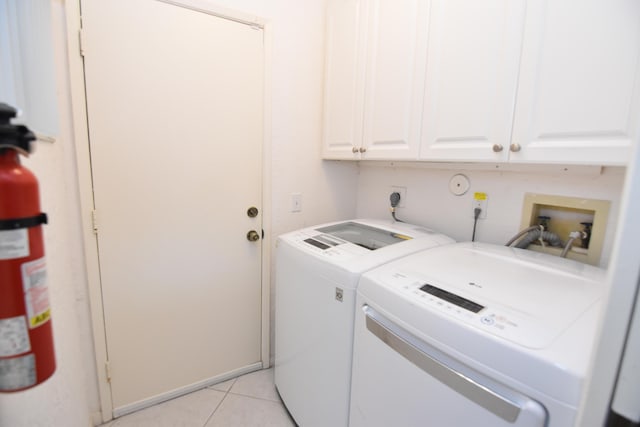 laundry area with washer and dryer, light tile patterned flooring, and cabinets