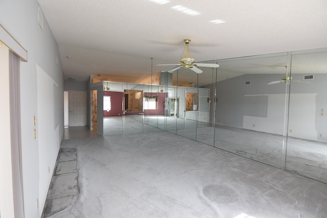 empty room featuring a textured ceiling, concrete floors, ceiling fan, and lofted ceiling