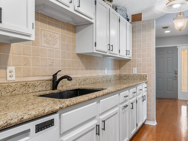 kitchen featuring white cabinets, sink, light hardwood / wood-style flooring, a textured ceiling, and dishwashing machine