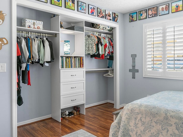 bedroom with a textured ceiling, dark hardwood / wood-style flooring, and a closet