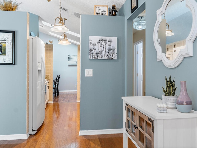 corridor with a textured ceiling and hardwood / wood-style flooring