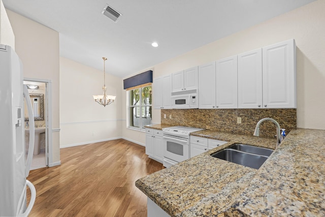 kitchen with pendant lighting, white appliances, sink, light wood-type flooring, and kitchen peninsula