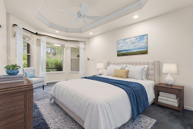 carpeted bedroom featuring ceiling fan and a raised ceiling