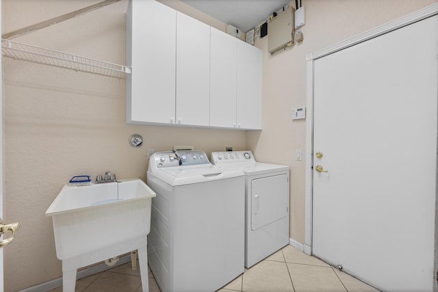 washroom featuring cabinets, light tile patterned floors, sink, and washing machine and dryer