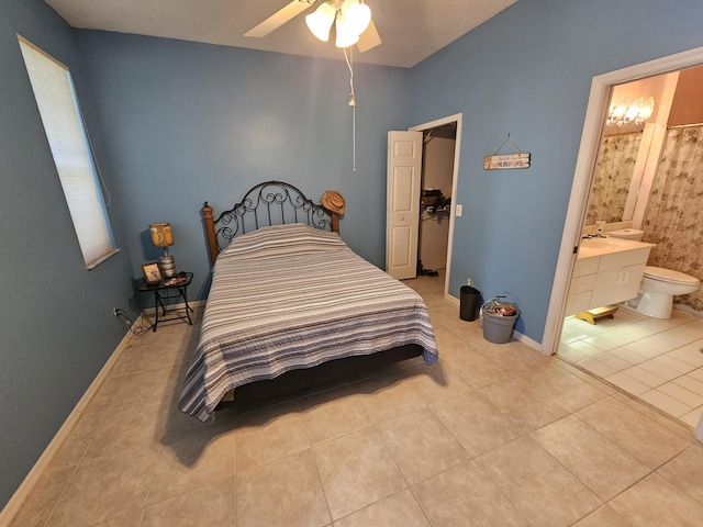 bedroom with ensuite bath, light tile patterned flooring, and ceiling fan