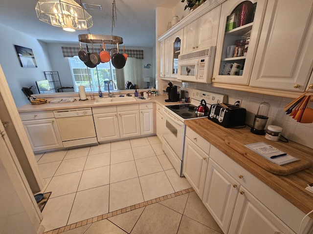 kitchen featuring sink, white appliances, light tile patterned flooring, hanging light fixtures, and a notable chandelier