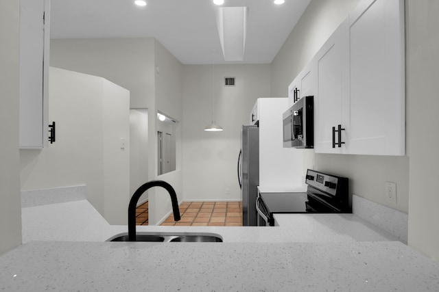 kitchen with sink, light tile patterned floors, appliances with stainless steel finishes, light stone counters, and white cabinetry