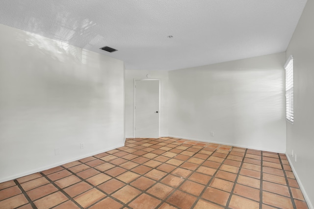 tiled spare room featuring a textured ceiling