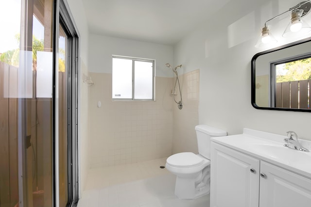 bathroom featuring toilet, tile patterned flooring, vanity, and tiled shower