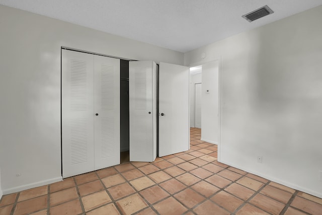 unfurnished bedroom featuring light tile patterned floors, a textured ceiling, and a closet