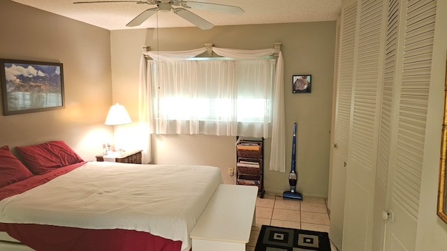 bedroom with a textured ceiling, a closet, ceiling fan, and light tile patterned flooring