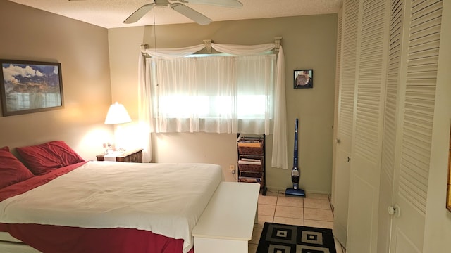 bedroom featuring ceiling fan, light tile patterned flooring, a textured ceiling, and a closet