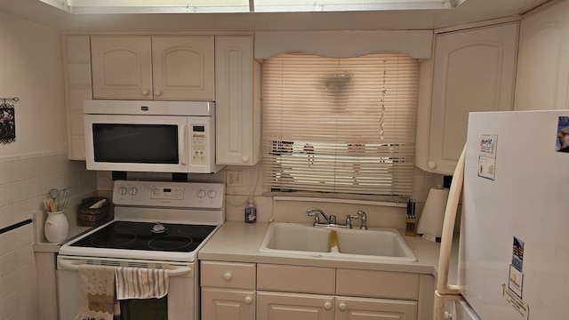 kitchen featuring white cabinetry, sink, and white appliances