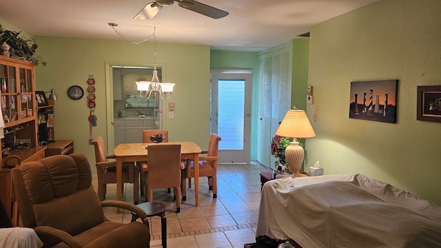 dining space featuring light tile patterned floors, ceiling fan with notable chandelier, and sink