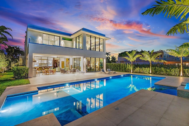 pool at dusk featuring a patio area