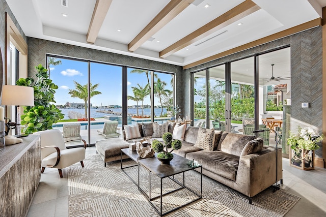 living room with a water view, tile walls, ceiling fan, and beamed ceiling