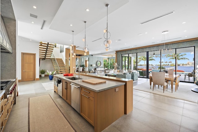 kitchen featuring dishwasher, a center island with sink, gas cooktop, sink, and hanging light fixtures