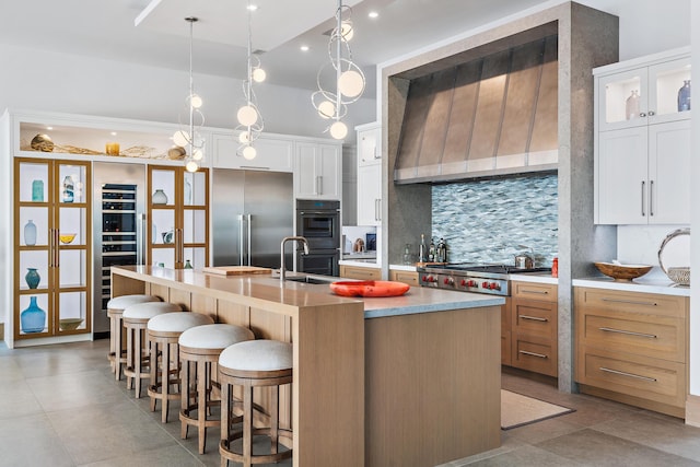 kitchen featuring white cabinetry, stainless steel appliances, tasteful backsplash, and a kitchen island with sink