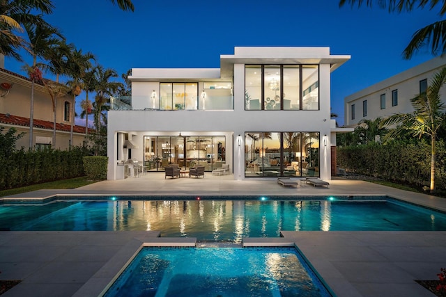 back of house featuring a balcony, a pool with hot tub, and a patio