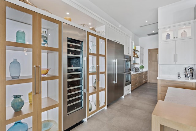 kitchen with wine cooler, double oven, white cabinets, and high end fridge