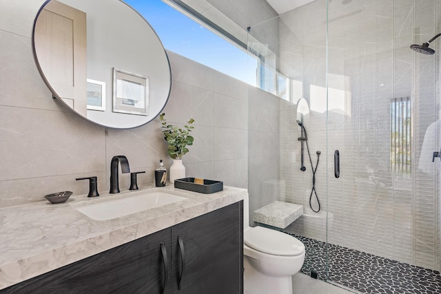 bathroom with toilet, tasteful backsplash, tiled shower, tile walls, and vanity