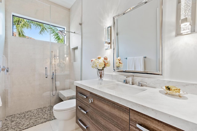 bathroom featuring toilet, a shower with door, tile patterned floors, and vanity