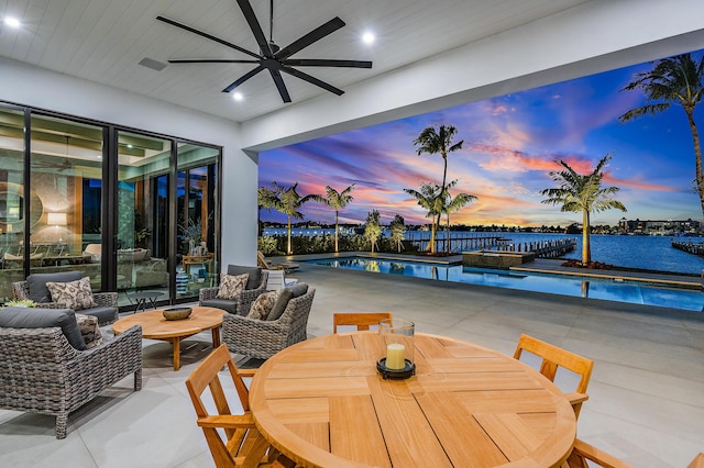 patio terrace at dusk featuring a water view and an outdoor living space