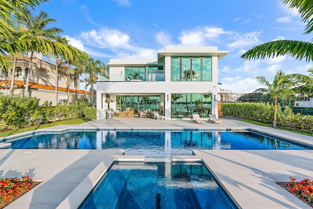 back of house with a balcony, a pool with hot tub, and a patio