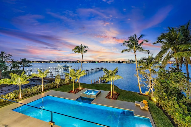 pool at dusk featuring a water view, a dock, a yard, and an in ground hot tub