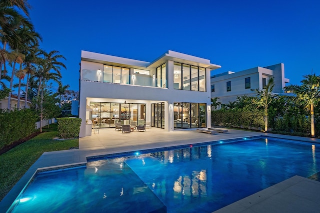 rear view of property with a fenced in pool and a patio