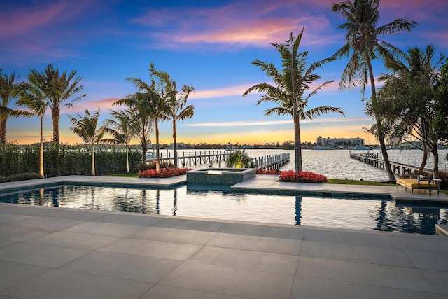 pool at dusk featuring a water view and a boat dock