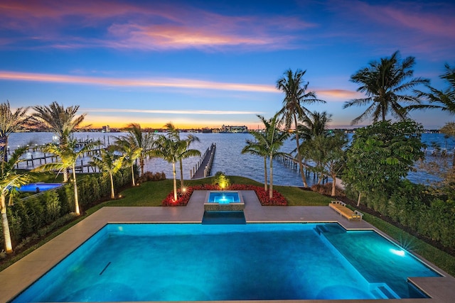 pool at dusk with a water view and an in ground hot tub