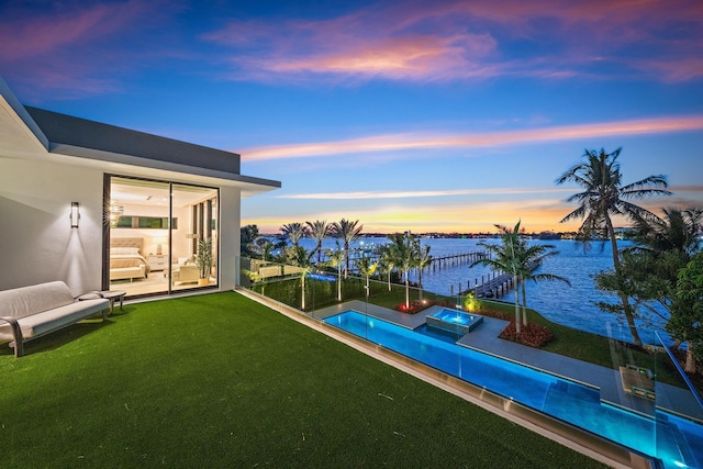 pool at dusk with a water view and a lawn