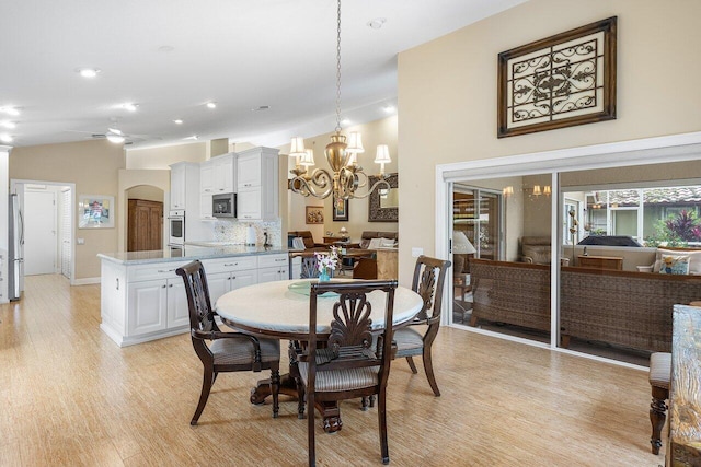 dining room featuring ceiling fan with notable chandelier and light hardwood / wood-style floors