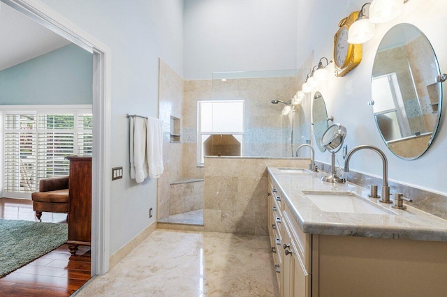 bathroom with a tile shower, vanity, hardwood / wood-style flooring, and lofted ceiling