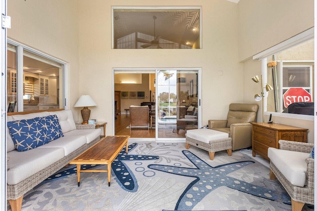 living room with hardwood / wood-style flooring, ceiling fan, and high vaulted ceiling