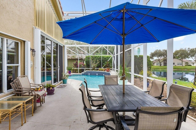 view of swimming pool featuring glass enclosure, a patio area, and a water view