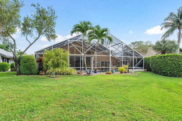 rear view of house featuring a lanai and a lawn