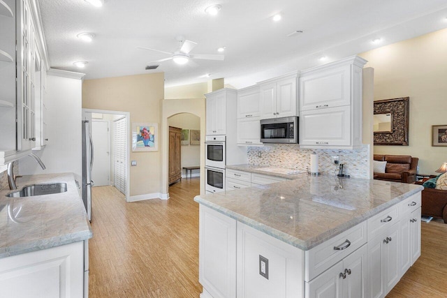 kitchen featuring white cabinets, sink, light stone countertops, appliances with stainless steel finishes, and light hardwood / wood-style floors