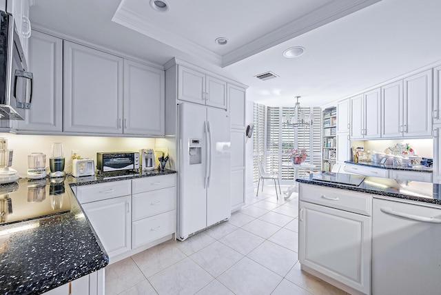 kitchen featuring white appliances, white cabinets, ornamental molding, a tray ceiling, and decorative light fixtures