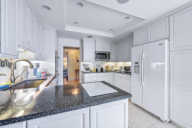 kitchen with appliances with stainless steel finishes, a tray ceiling, white cabinetry, and sink