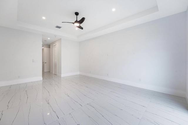 unfurnished room featuring ceiling fan and a raised ceiling