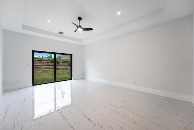 empty room featuring a raised ceiling and ceiling fan