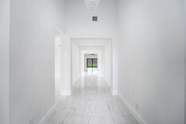 hallway featuring a towering ceiling and an inviting chandelier