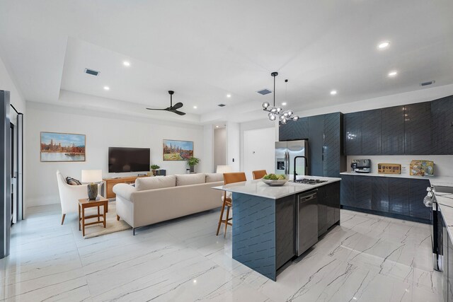 kitchen featuring ceiling fan with notable chandelier, hanging light fixtures, sink, an island with sink, and appliances with stainless steel finishes