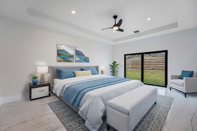 bedroom with a tray ceiling, access to exterior, and ceiling fan