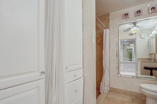 bathroom featuring curtained shower, ceiling fan, sink, tile patterned flooring, and toilet