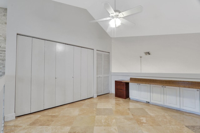 interior space with high vaulted ceiling, ceiling fan, and multiple closets