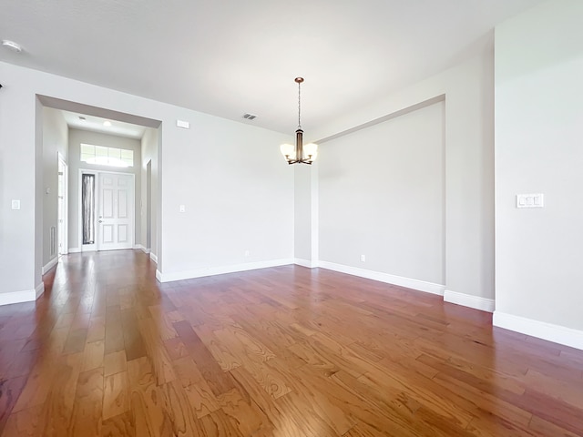 unfurnished room featuring dark hardwood / wood-style floors and a notable chandelier