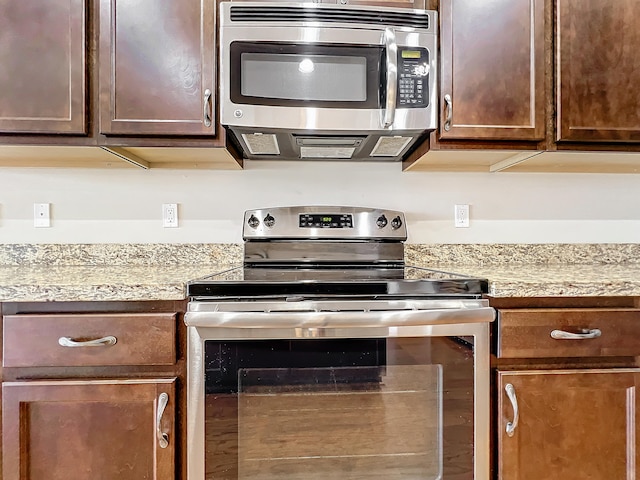 kitchen featuring dark brown cabinetry, stainless steel appliances, and light stone counters